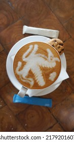 flat white cappuccino coffee mug with latte art in the shape of a pegasus horse on a wooden table. Coffee latte art with Pegasus horse art, flat lay, top view