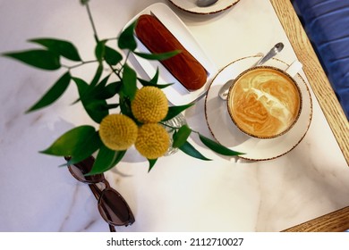 A flat white with chocolate eclair on a white marble table in a cafe