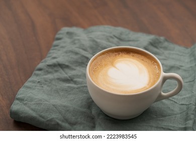 Flat White In White Cup With Simple Latte Art On Walnut Wood Table With Turquoise Napkin, Shallow Focus