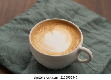 Flat White In White Cup With Simple Latte Art On Walnut Wood Table With Turquoise Napkin, Shallow Focus