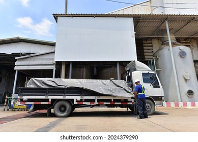 Flatbed Truck loaded with Steel and Truck Driver covering with a Black Tarp and straps before logistics import export to Customer
