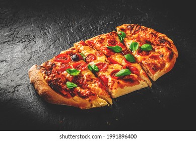Pizza mit Mozzarella, Tomaten, Pfeffer, Gewürzen und Basilikum. Italienische Pizza. Pizza Margherita oder Margarita auf dunkelgrauem, schwarzem Hintergrund