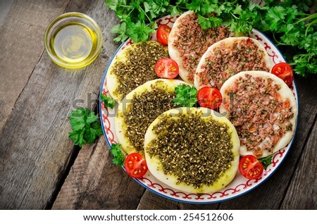 Flatbread with zaatar and meat(lahmacun) in ornament plate with parsley and tomatoes on wooden background. Arabian cuisine