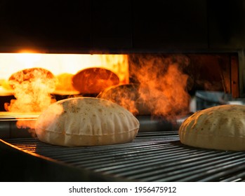Flatbreads. fresh pita taken from oven. Quboos Arabic Bread making process the dough cut in to round shape passing through the conveyor belt. Fresh round pita is taken from the oven. bread of factory  - Shutterstock ID 1956475912