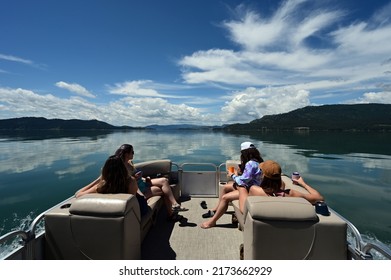 Flathead Lake, Montana - June 21, 2022: Four Young Women Enjoy Ride On Pontoon Boat On Lake's Calm Water On Sunny Summer Morning.