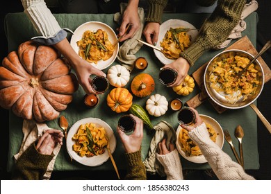 Flat-lay Of Autumn Dinner For Gathering Or Thanksgiving Day Celebration. Friends Clinking Glasses With Red Wine And Eating Butternut Squash Pasta With Sausage And Sage Over Linen Tablecloth, Top View