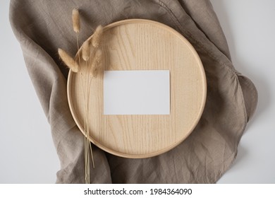 Flatlay of blank paper business card on neutral beige blanket background. Business template