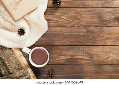 Flatlay Composition With White Knitted Scarf, Cup Of Tea, Firewood, Gift Box On Wooden Desk Table. Hygge Style, Cozy Autumn Or Winter Holiday Concept. Flat Lay, Top View, Overhead.