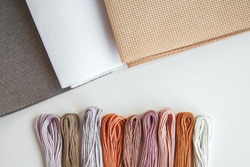 flatlay creativity: canva aida beige, gray and white and multi-colored floss thread, all for cross stitching, an Arts & Entertainment Photo by Evgeniia Primavera