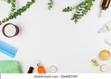 Flatlay frame arrangement with eucalyptus branches, candles, oils, serums and various beauty products  for hair and body. White background, copyspace - Shutterstock ID 1064087549