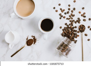 Flatlay Of Fresh Cups Of Espresso And Milk Coffee, Creamer, Coffee Beans And Spoon On Marble Background, Selective Focus