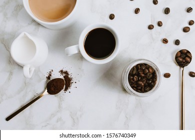 Flatlay Of Fresh Cups Of Espresso And Milk Coffee, Creamer, Coffee Beans And Spoon On Marble Background, Selective Focus