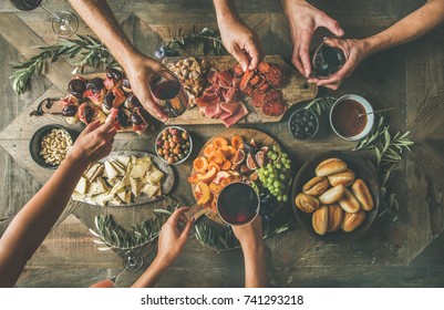 Flat-lay Of Friends Hands Eating And Drinking Together. Top View Of People Having Party, Gathering, Celebrating Together At Vintage Wooden Rustic Table Set With Different Wine Snacks And Fingerfoods