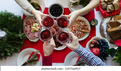 Flat-lay Of Friends Hands Toasting With Glasses Of Red Wine. Family Gathering Concept. Traditional Italian Christmas Dinner Food - Lentils With Cotechino, Antipasti, Panettone And Fruits. Top View.