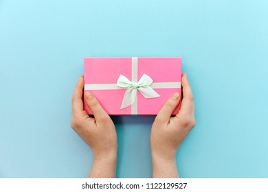Flatlay holidays giftbox present in woman hands on the pastel blue background for holiday, christmas, birthday party
