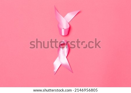 Flat-lay Image of Two Small Pink Ribbons Against Coral Background as Symbol of Breast  Cancer Awareness During Cancer Fight  Campaign. Horizontal Composition