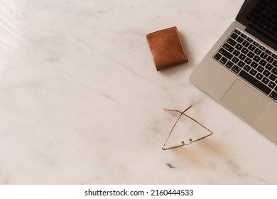 Flatlay Of Laptop, Wallet, Glasses On Marble Table. Home Office Desk Workspace. Lady, Girl Boss Aesthetic Business, Work Concept. Flat Lay, Top View