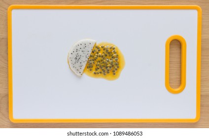 Flatlay Of Passionfruit Seeds And White Dragon Fruit On A White Cutting Board.