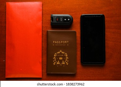 A Flatlay Picture Of Bribery Gift Concept Using Red Envelope Money, Blank Smartphone, Remote Car Key And Passport. International Anti-Corruption Day Concept.