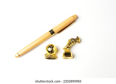 Flatlay Picture Of Pen With Miniature Golden Ball And Boots On White Background. Signing Player And Transfer Window Concept.