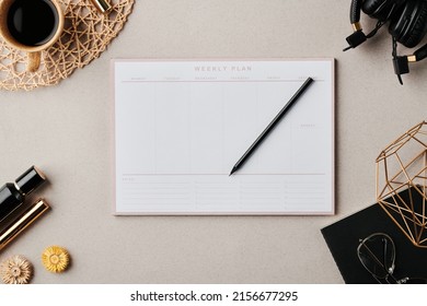 Flatlay of planner with pencil surrounded by cup of coffee, black copybook with eyeglasses and handmade vase and other objects