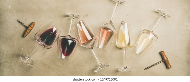 Flachlage aus Rot, Rose und Weißwein in Gläsern und Korkschrauben auf grauem Betonhintergrund, Draufsicht, breite Zusammensetzung. Weinbar, Weinkeller, Weindegustation-Konzept