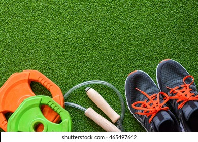 Flatlay of sport equipments on the green grass with copy space for putting texts and content. The set of sport equipments comprises sneakers, weights, and a jumping rope. - Powered by Shutterstock
