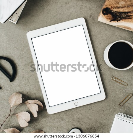 Flatlay of tablet with copy space screen mock up. Top view home office desk workspace decorated with eucalyptus, wooden board and stationery.