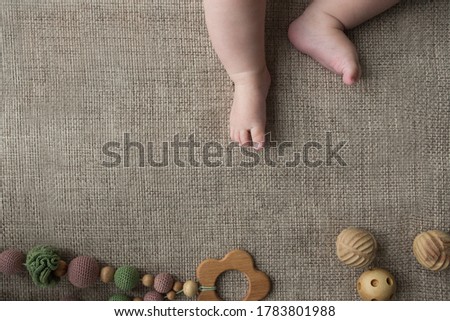 Flatlay with tiny chubby newborn baby legs and knitted and wood handmade toys. Natural calm colors, copy space avilable