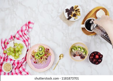 Flatlay Of Vegan Breakfast With Plant Based Yogurt Bowls Topped With Kiwi Slices, Granola, Chia Seeds, Smoothie Bottle And Coffee With Soy Milk On Marble Background 