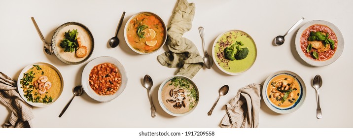 Flat-lay Of Vegetarian Creamy Homemade Soup And Spoons Over White Plain Table Background, Top View. Autumn And Winter Creamy Vegan Soups, Fall And Winter Vegetarian Food Menu Concept