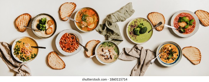 Flat-lay Of Vegetarian Creamy Homemade Soups Variety With Bread Slices Over White Plain Background, Top View. Autumn And Winter Creamy Vegan Soups, Fall And Winter Vegetarian Food Menu Concept