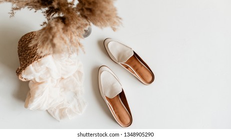 Flatlay of white shoes on white surface.
