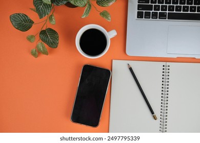 flatlay of a workplace with A cup of coffee, a laptop and a notebook, on a plain background. Education, business and office concept. 