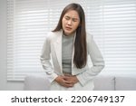 Flatulence, abdomen asian young business woman in suit at home, hand in stomach ache, expression face suffer from food poisoning, abdominal pain and colon problem, gastritis or diarrhoea, inflammation