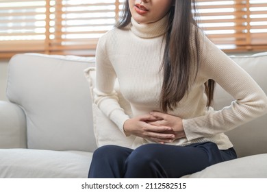 Flatulence asian young woman, girl hand in stomach ache, suffer from food poisoning, abdominal pain and colon problem, gastritis or diarrhoea. Patient belly, abdomen or inflammation, concept. - Shutterstock ID 2112582515