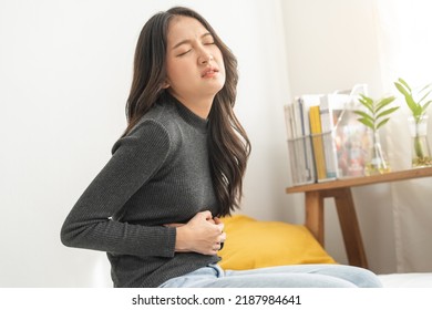 Flatulence asian young woman, girl hand in stomach ache, suffer from food poisoning, abdominal pain and colon problem, gastritis or diarrhoea. Patient belly, abdomen or inflammation, concept. - Shutterstock ID 2187984641