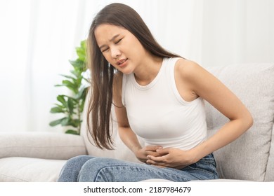 Flatulence asian young woman, girl hand in stomach ache, suffer from food poisoning, abdominal pain and colon problem, gastritis or diarrhoea. Patient belly, abdomen or inflammation, concept. - Shutterstock ID 2187984679