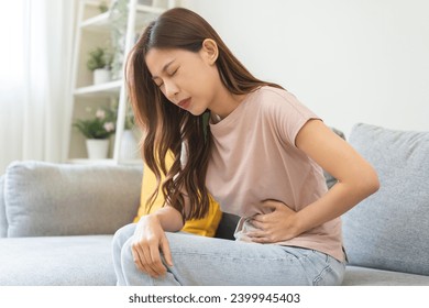 Flatulence asian young woman intolerance hand in stomach ache, suffer from food poisoning, abdominal pain and colon problem, gastritis or diarrhoea when at home. Patient belly, abdomen or inflammation - Powered by Shutterstock