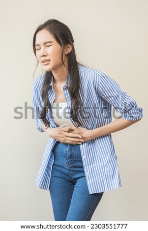 Flatulence asian young woman intolerance hand in stomach ache, suffer from food poisoning, abdominal pain and colon problem, gastritis or diarrhoea when at home. Patient belly, abdomen or inflammation