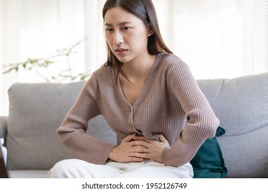 Flatulence young asian woman, girl hand in stomach ache, suffer from food poisoning, abdominal pain and colon problem, gastritis or diarrhoea. Patient belly, abdomen or inflammation, concept. - Shutterstock ID 1952126749