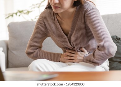 Flatulence young asian woman, girl hand in stomach ache, suffer from food poisoning, abdominal pain and colon problem, gastritis or diarrhoea. Patient belly, abdomen or inflammation, concept. - Shutterstock ID 1984323800