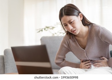Flatulence young asian woman, girl hand in stomach ache, suffer from food poisoning, abdominal pain and colon problem, gastritis or diarrhoea. Patient belly, abdomen or inflammation, concept. - Shutterstock ID 1993650998