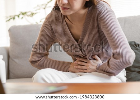 Flatulence young asian woman, girl hand in stomach ache, suffer from food poisoning, abdominal pain and colon problem, gastritis or diarrhoea. Patient belly, abdomen or inflammation, concept.