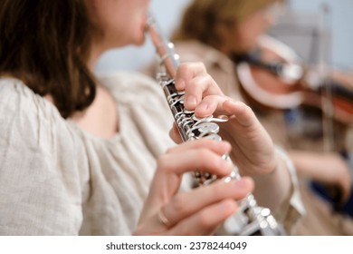 The flautist's hand, seen in macro view, gracefully glides along the flute's keys, producing enchanting music in the orchestra. - Powered by Shutterstock