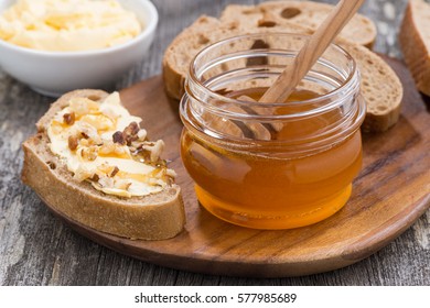 flavored honey, bread with butter and grape on wooden board, close-up, horizontal
