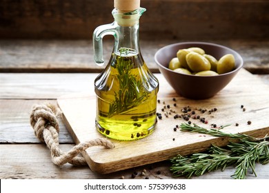 Flavored olive oil with rosemary and pepper on wooden background.