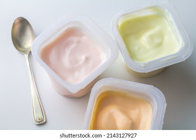 Flavoured yogurt in plastic cups - colourful fruit flavoured yogurt cups isolated on white with copy space - top view photo
