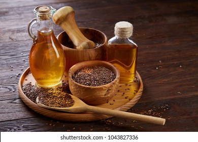 Flax seeds in bowl and flaxseed oil in glass bottle on wooden background, top view, close-up, selective focus