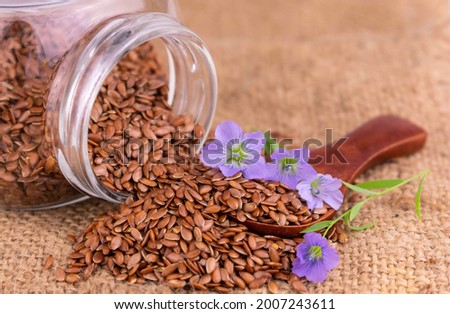 Flax seeds are poured out of a glass jar. Concept of natural vitamins and microelements.
Close-up.